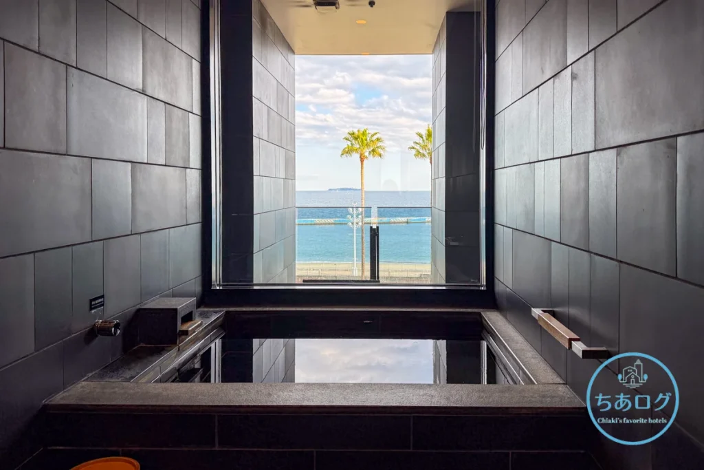 熱海パールスターホテル客室のオーシャンビュー・ビューバス（客室露天風呂）。ガラス張りの浴室から、海とヤシの木の景色を眺めながら入浴可能。