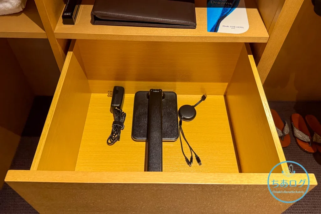 熱海パールスターホテルの引き出しに収納された、折りたたみ式のスリムLEDデスクライトとiPhone/Android対応のマルチ充電ケーブル。