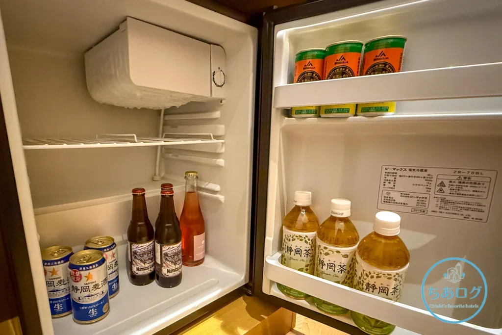 熱海パールスターホテルのフリーミニバー（冷蔵庫）。静岡麦酒や沼津ラガーなどの地ビール、静岡茶、中伊豆ワイナリー特製のオリジナル・ロゼスパークリングワインが並ぶ様子。