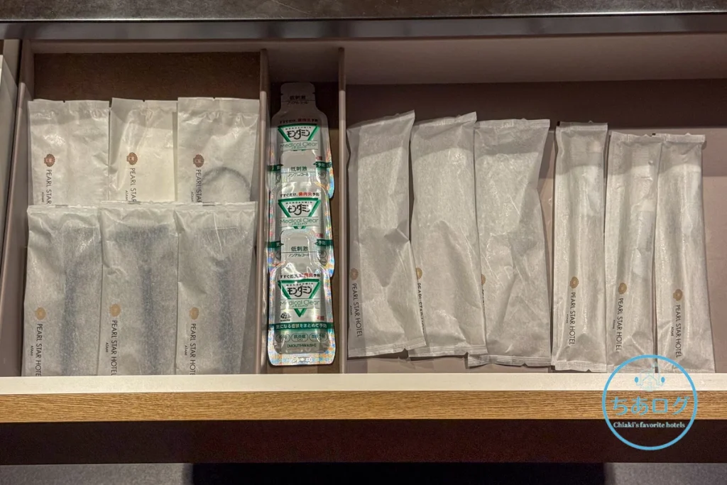 熱海パールスターホテルのアメニティ引き出し。ホテルロゴ入りの個包装に入った歯ブラシ、カミソリ、ブラシと、使い切りタイプのモンダミン・メディカルクリア。